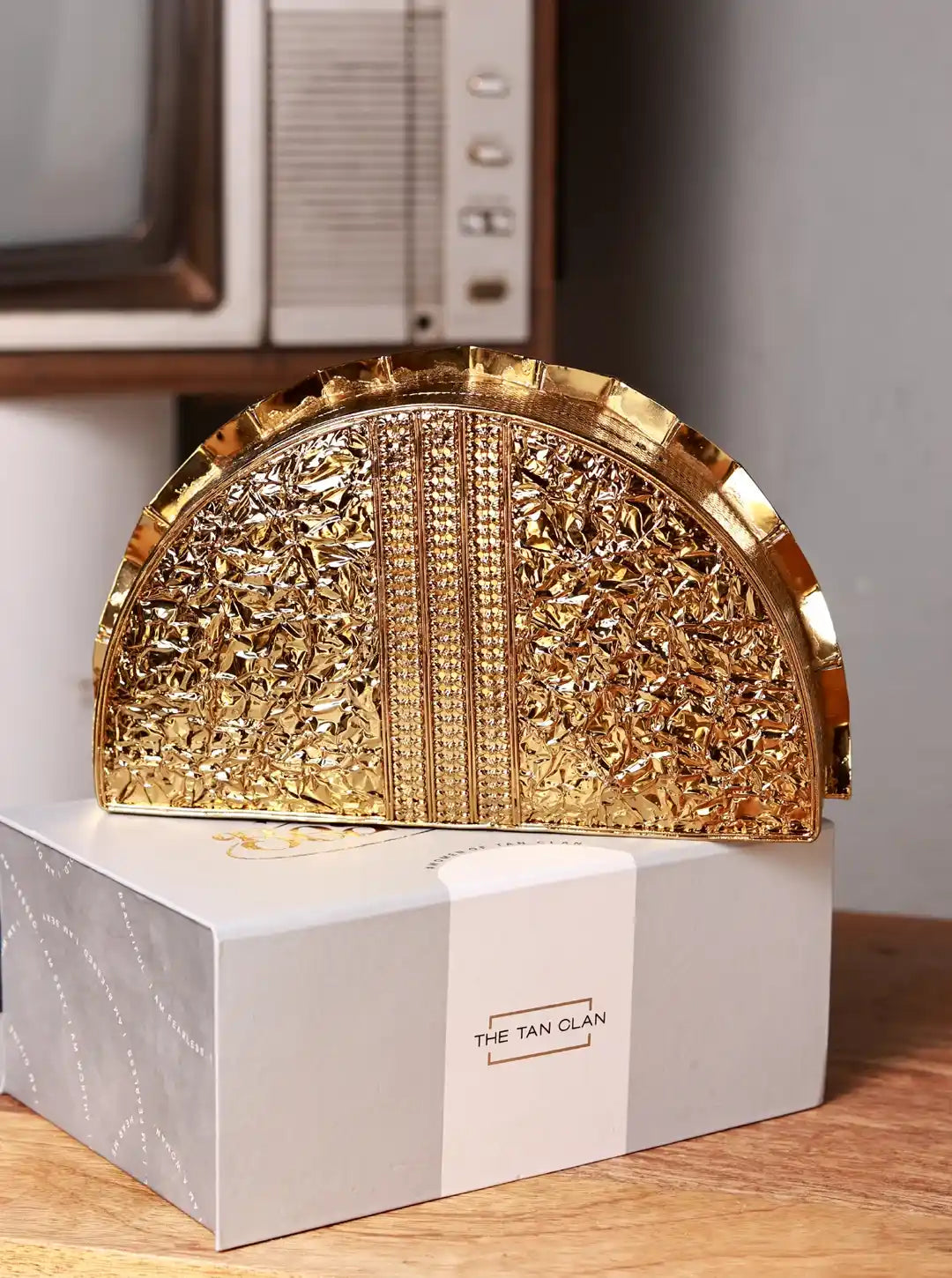 Gold decorative item on a white box with 'The Tan Clan' branding.
