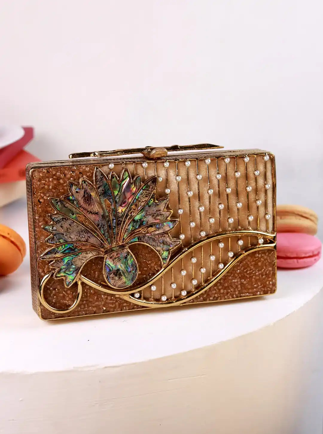 Decorative clutch bag with floral design and pearl embellishments on a white surface.