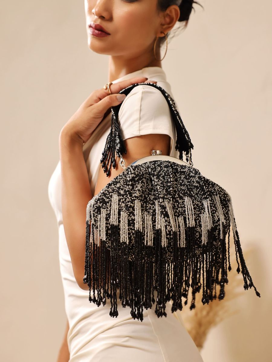 Black Batua bag with detachable handle from The Tan Clan, stylish leather accessory with sleek design and versatile carrying options.