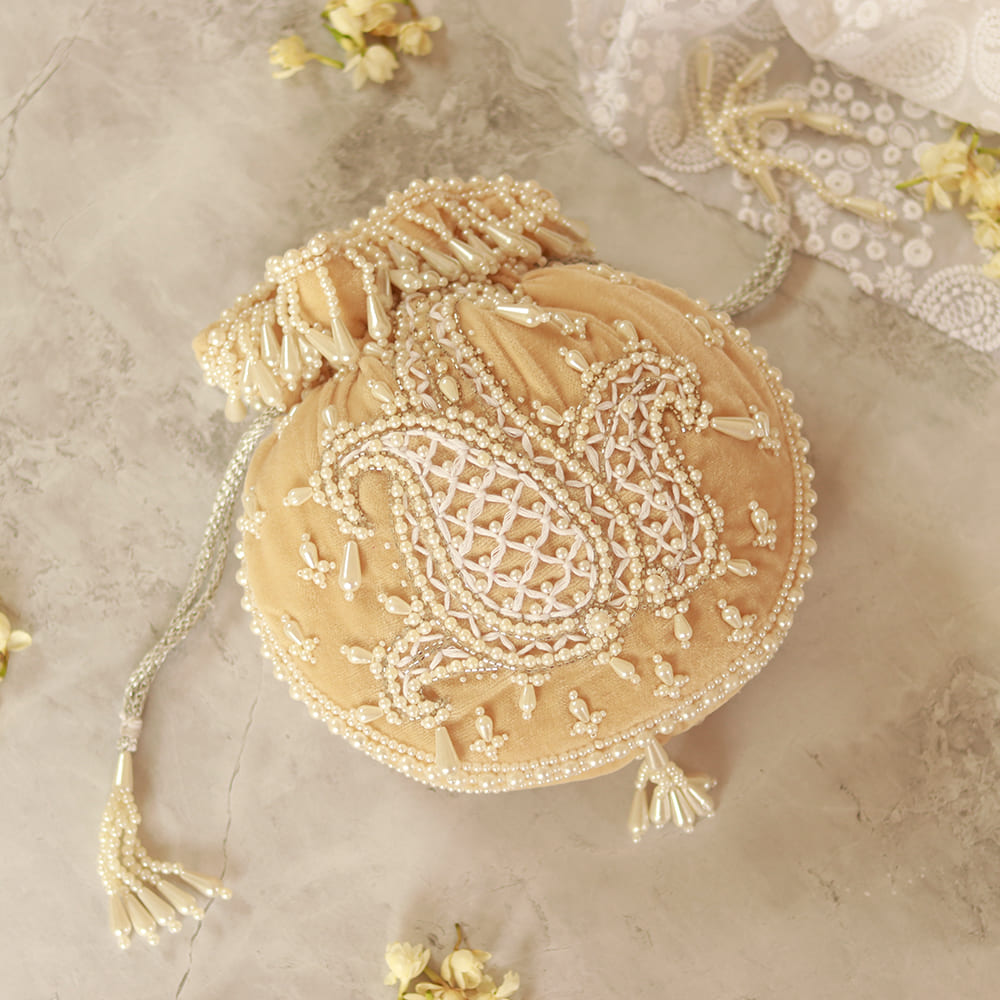 Beige Sukoon hand embroidered potli bag with pearl handle by The Tan Clan, showcasing intricate embroidery and elegant design.