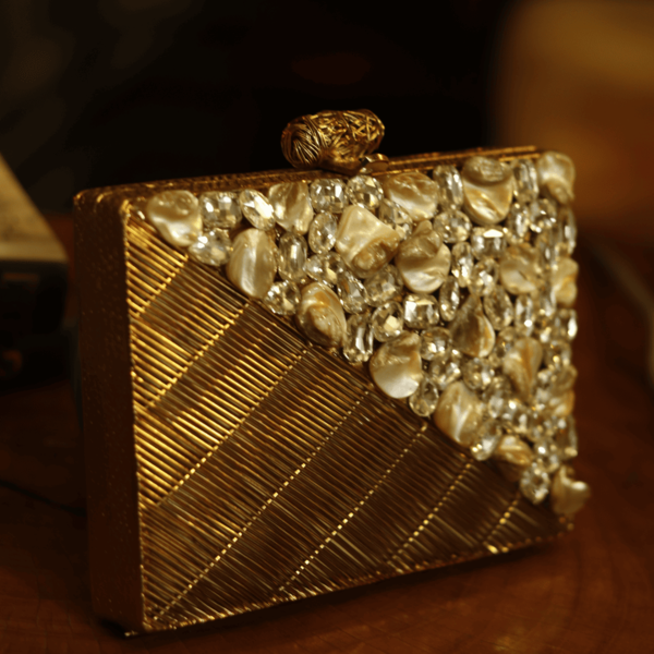 Golden brass clutch with intricate embellishments and tan accents, featuring a sleek, elegant design by The Tan Clan.