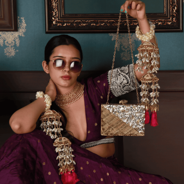 Golden brass clutch bag with embellished details from The Tan Clan's Eira collection, featuring intricate design and compact style.