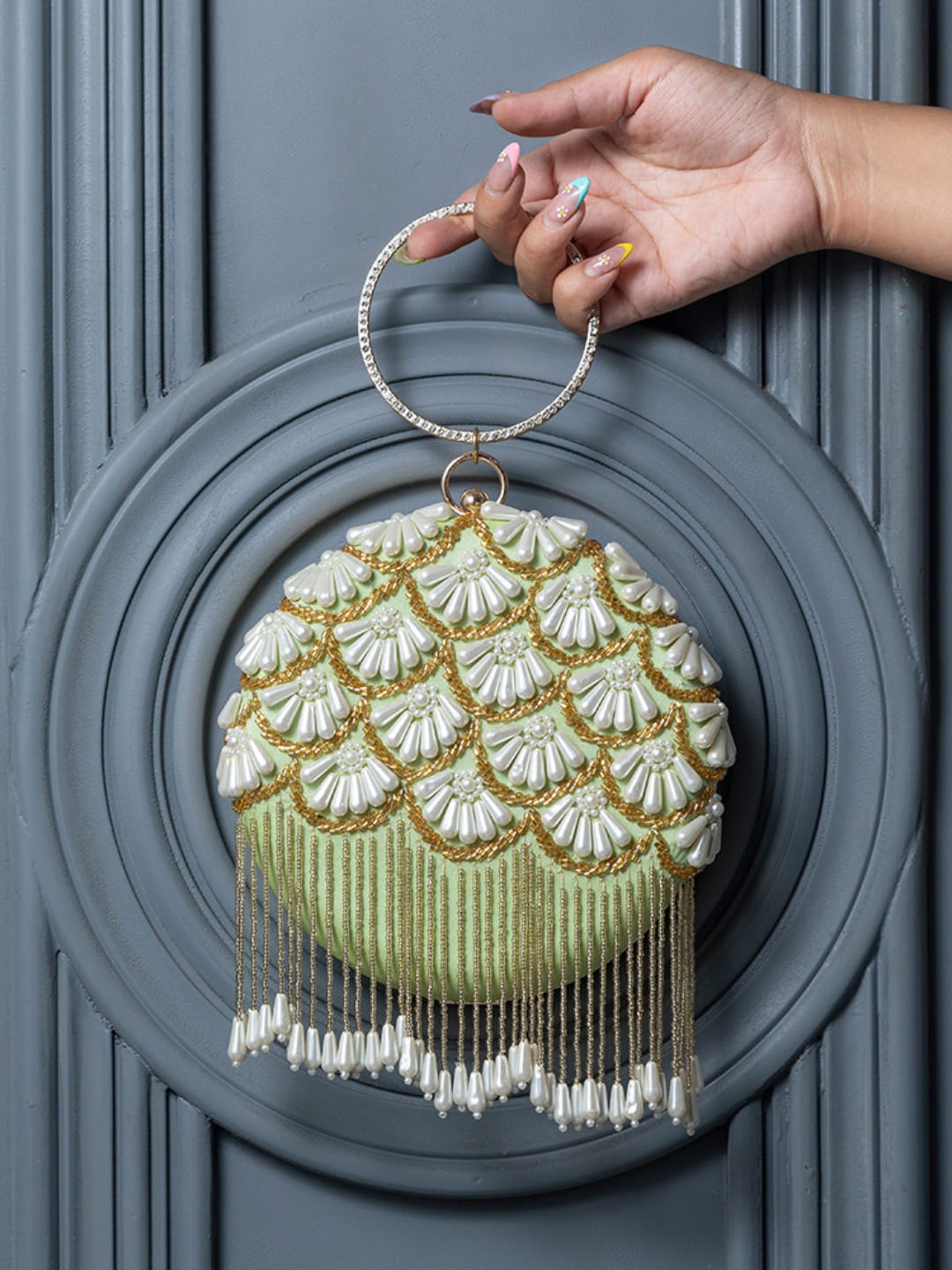 Light green Irsa round hand-embroidered clutch with tassels by The Tan Clan, featuring intricate embroidery and stylish design.