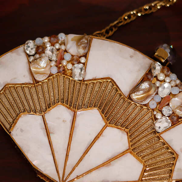 Golden brass mother of pearl clutch by The Tan Clan featuring intricate design and elegant compact style.