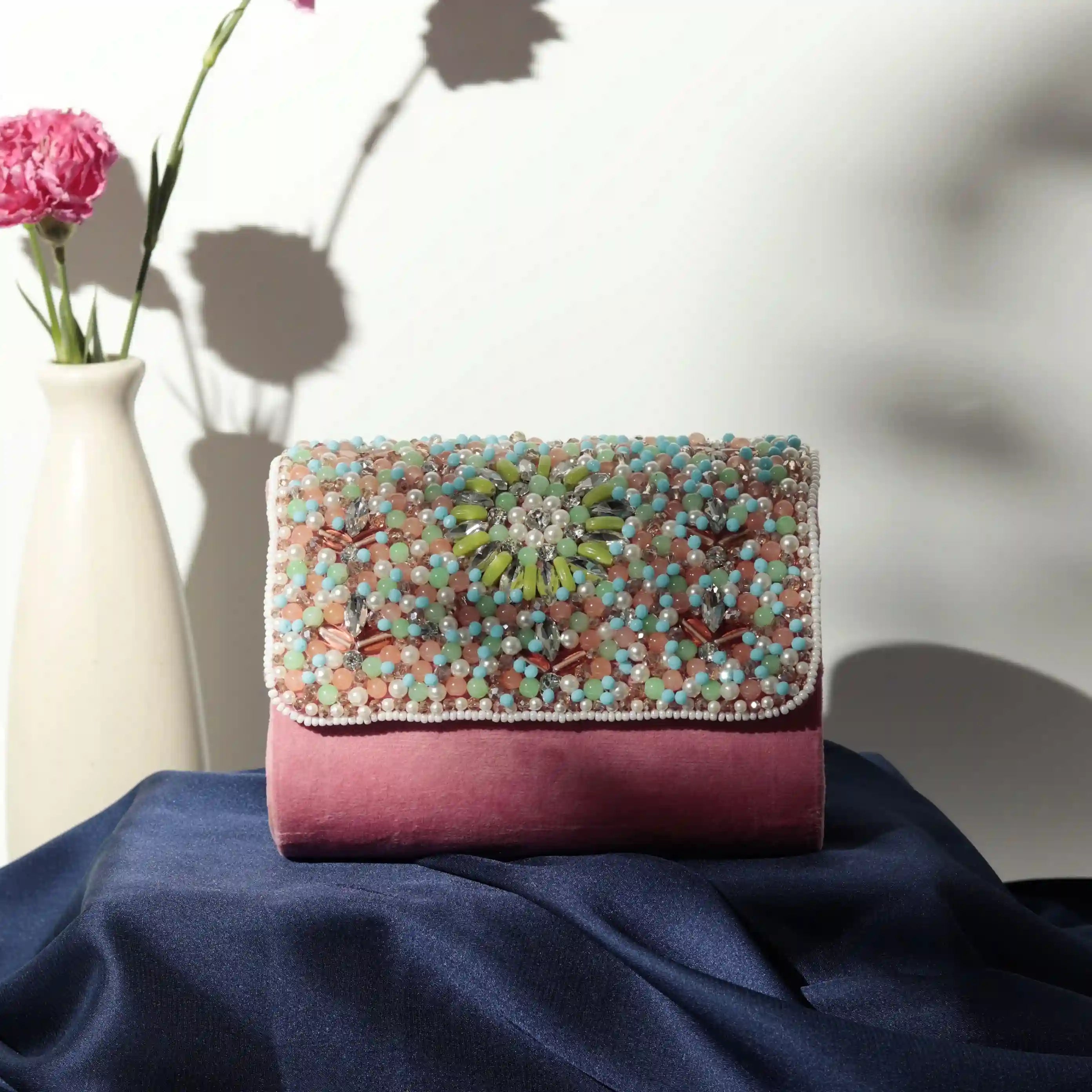 Rainbow embellished flap-over clutch bag by The Tan Clan, featuring vibrant rainbow decorations and a sleek design.