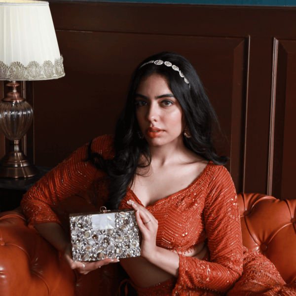Elegant brass clutch from The Tan Clan with intricate embellishments, featuring a sleek tan finish and decorative details.