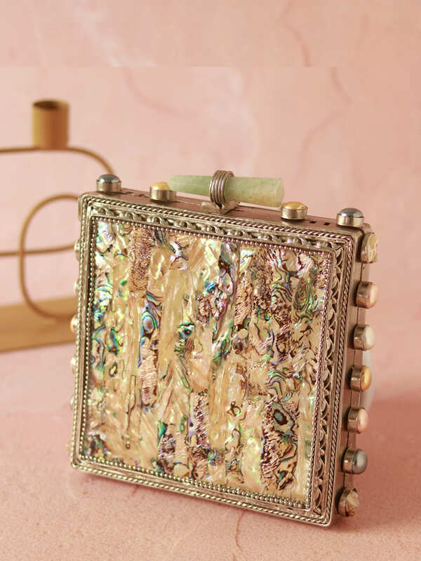 Salma Mother of Pearl Clutch by The Tan Clan featuring a sleek, elegant design with iridescent pearl surface and metallic accents.