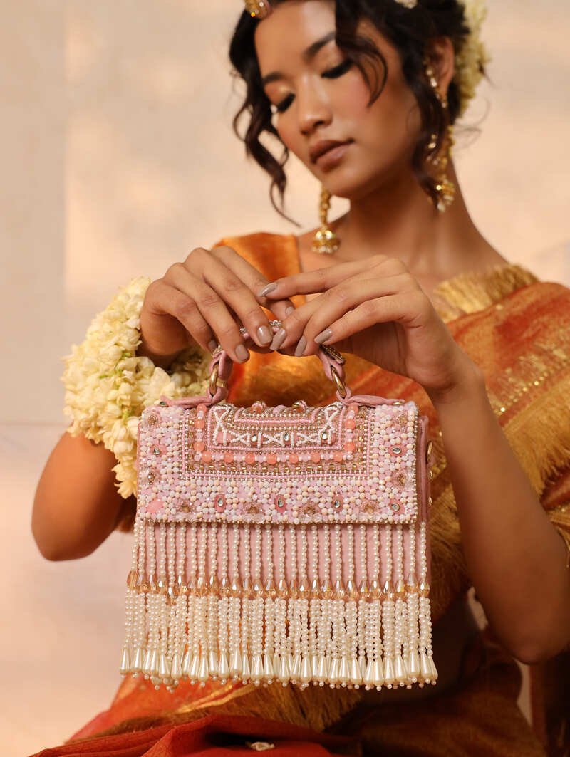 Pink flap-over bag with handle from The Tan Clan, featuring a sleek design and spacious interior for everyday use.