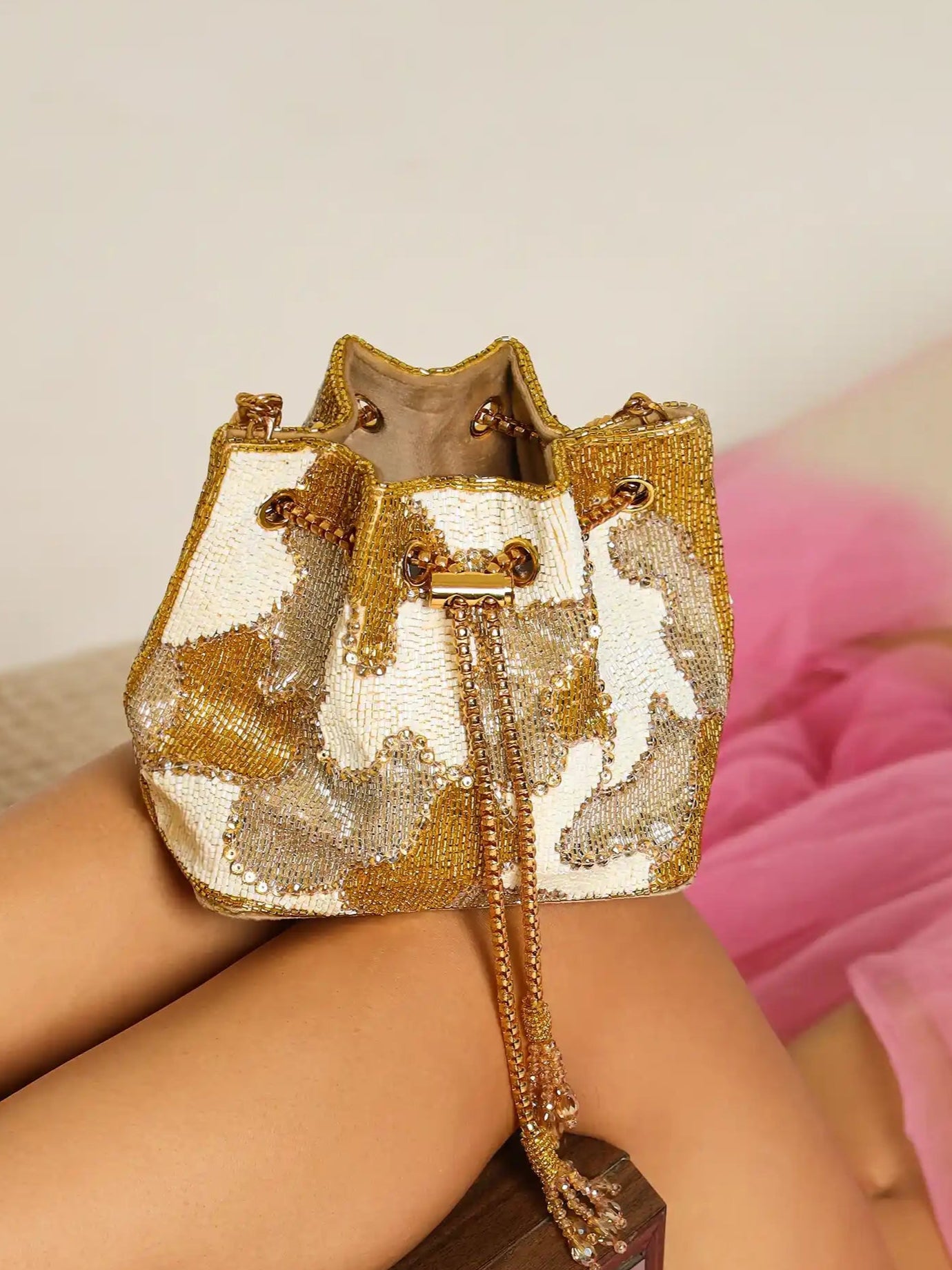 Person wearing a gold and white sequin bag with pink tulle skirt on a neutral background