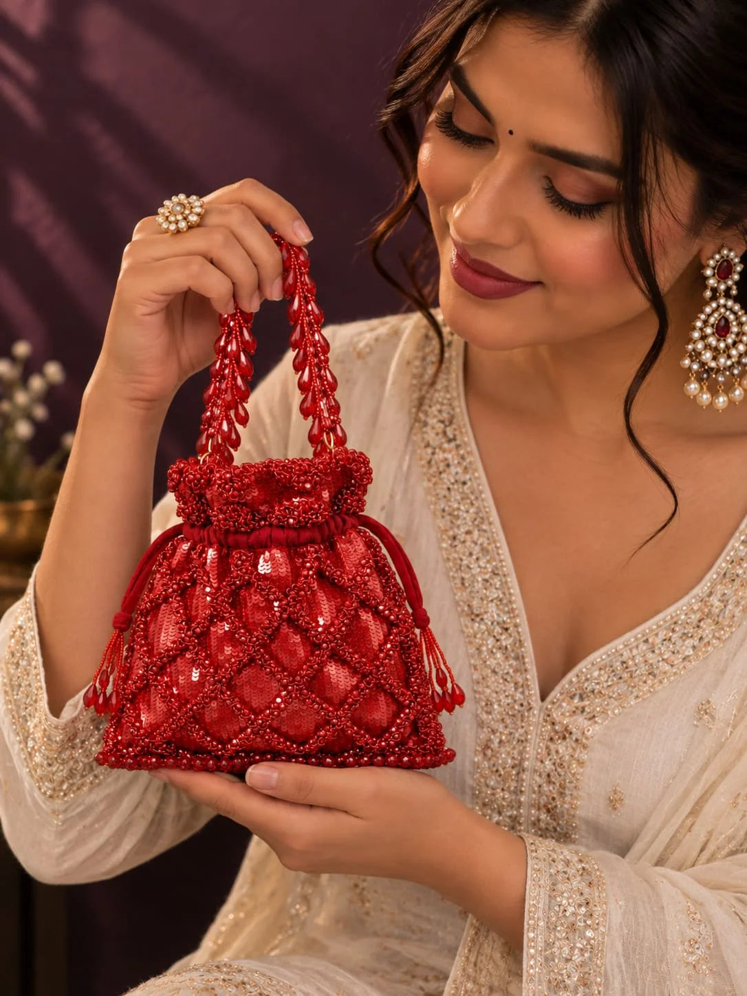 Red sequined tasselled potli bag from THE TAN CLAN featuring intricate embroidery and traditional design.