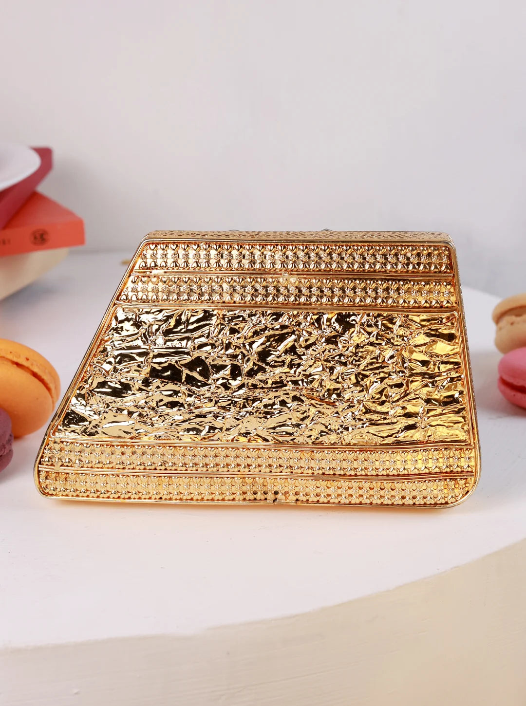 Gold clutch bag on a white surface with decorative elements