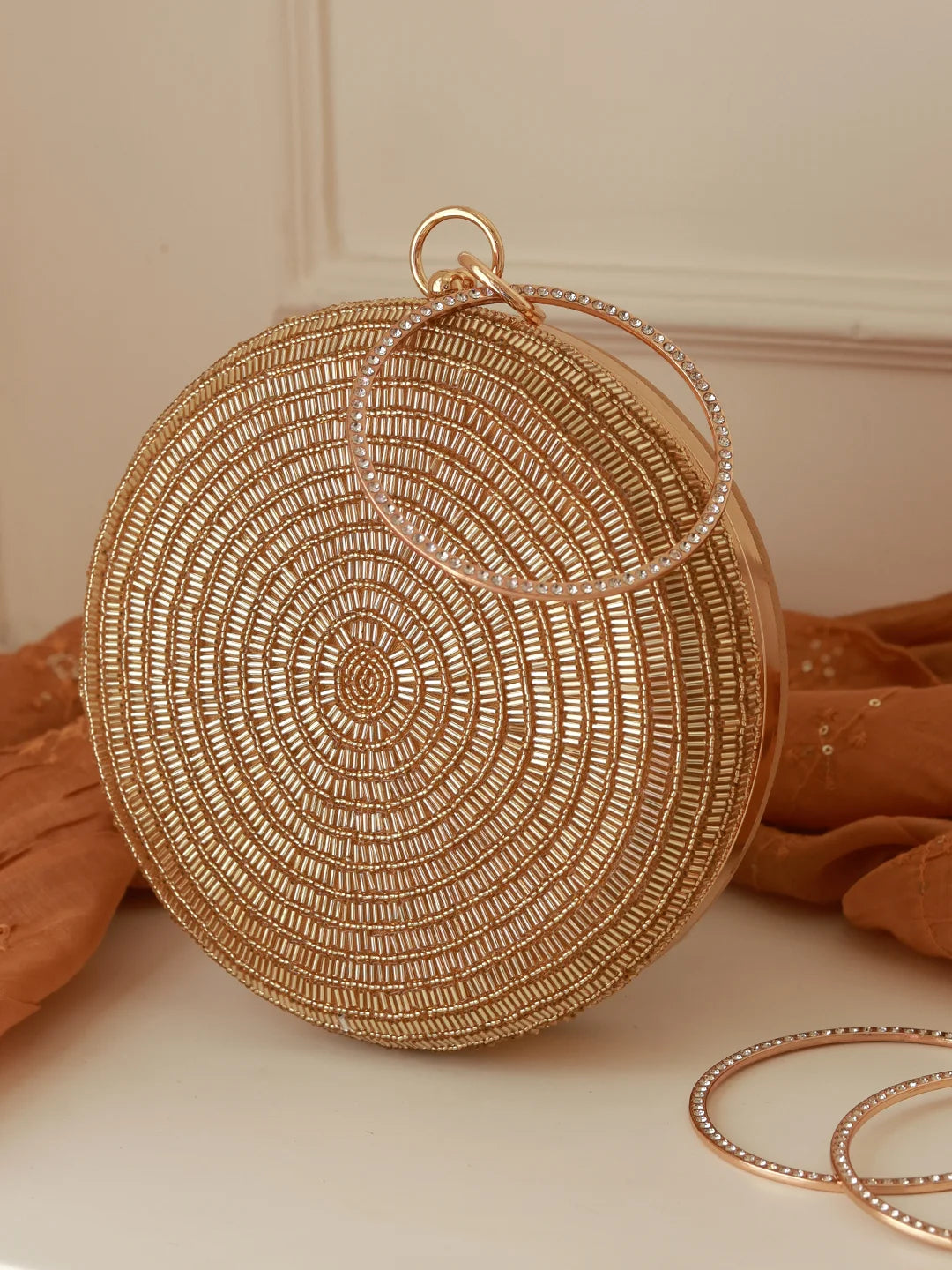 Round woven handbag with a gold handle on a neutral background