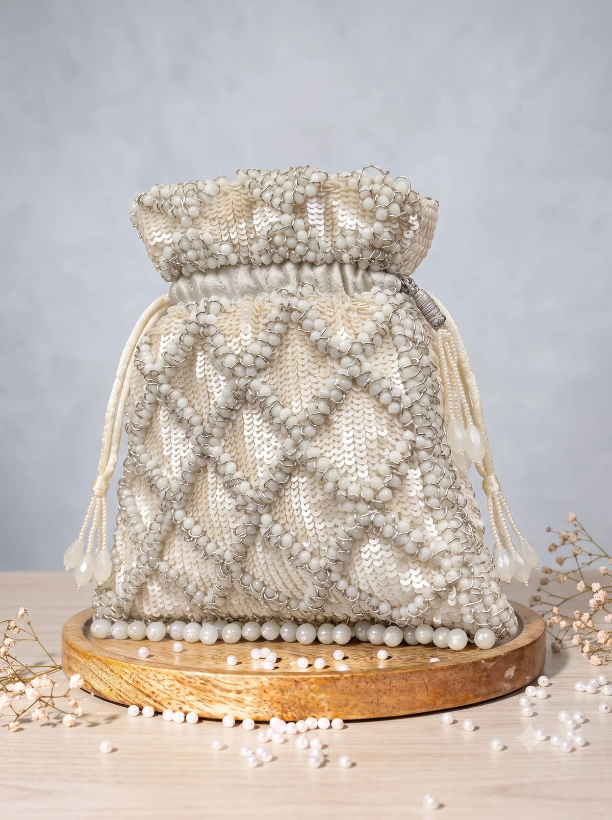 White sequined tasselled potli bag by THE TAN CLAN with intricate embroidery and decorative tassels, perfect for festive occasions.