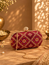 Red oval clutch bag from THE TAN CLAN with a sleek, minimalist design and polished finish.