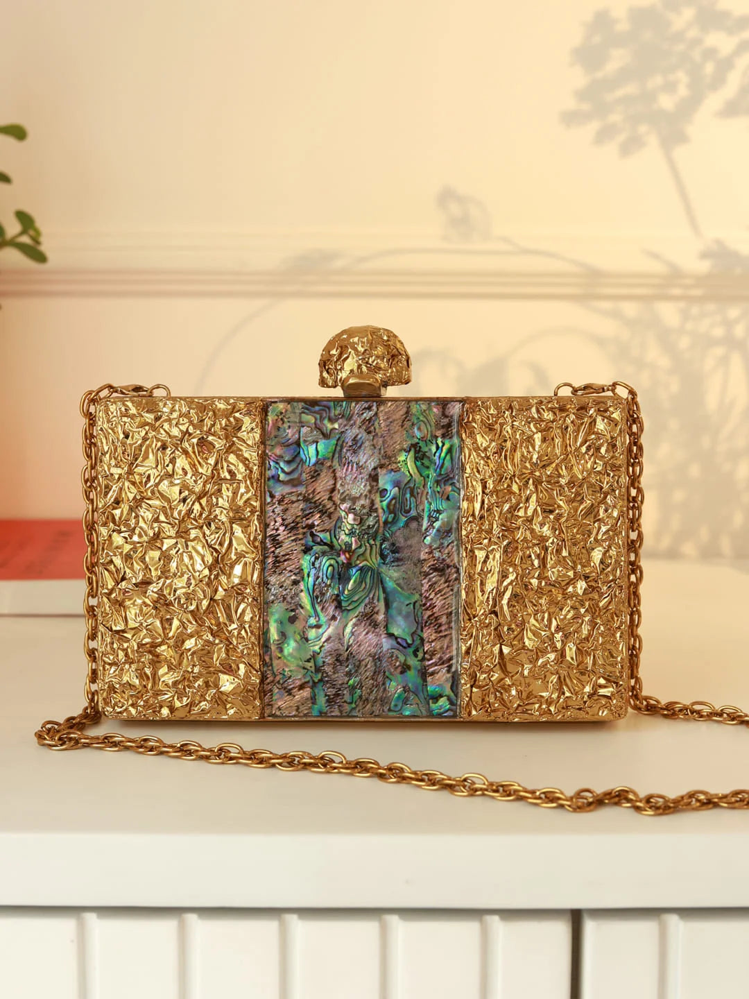 Gold clutch with a central colorful panel on a white surface