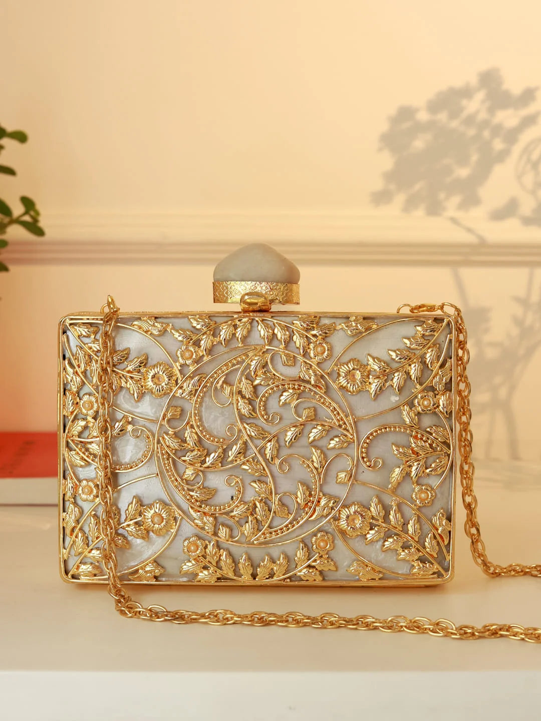 Gold and white handbag with intricate designs on a light background