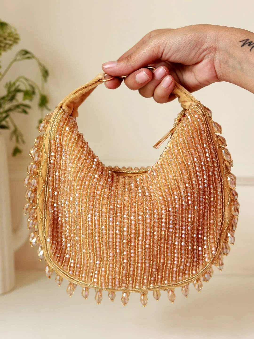 Gold beaded handbag held by a hand with a blurred background