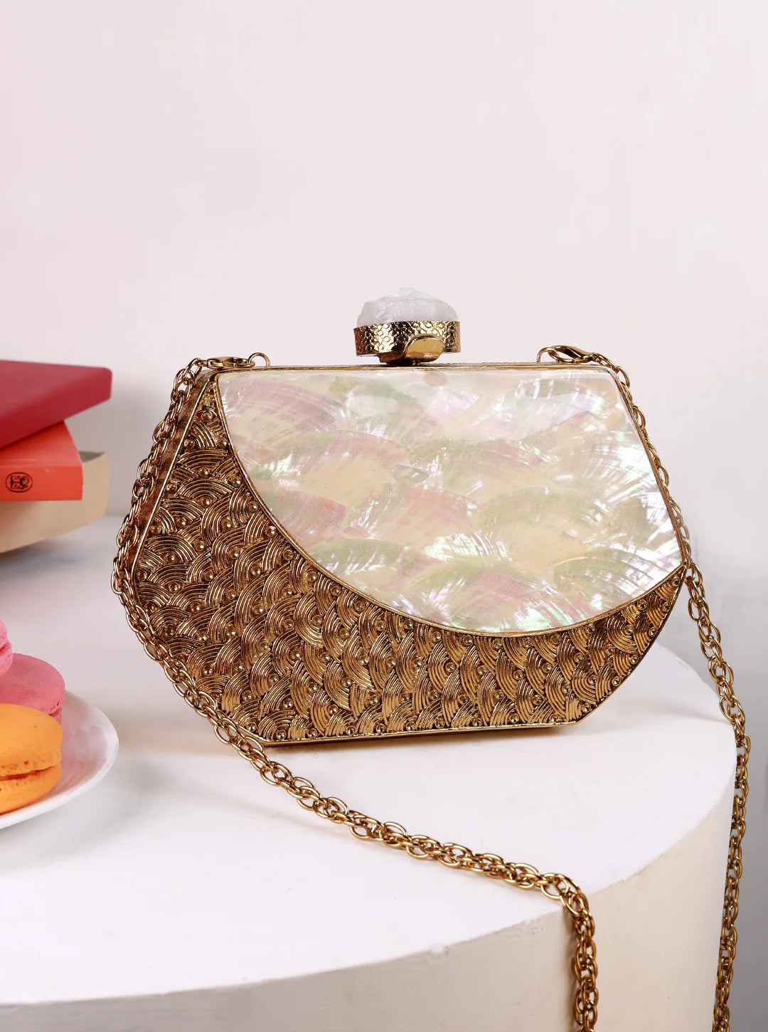 Gold clutch bag with a floral pattern on a white surface