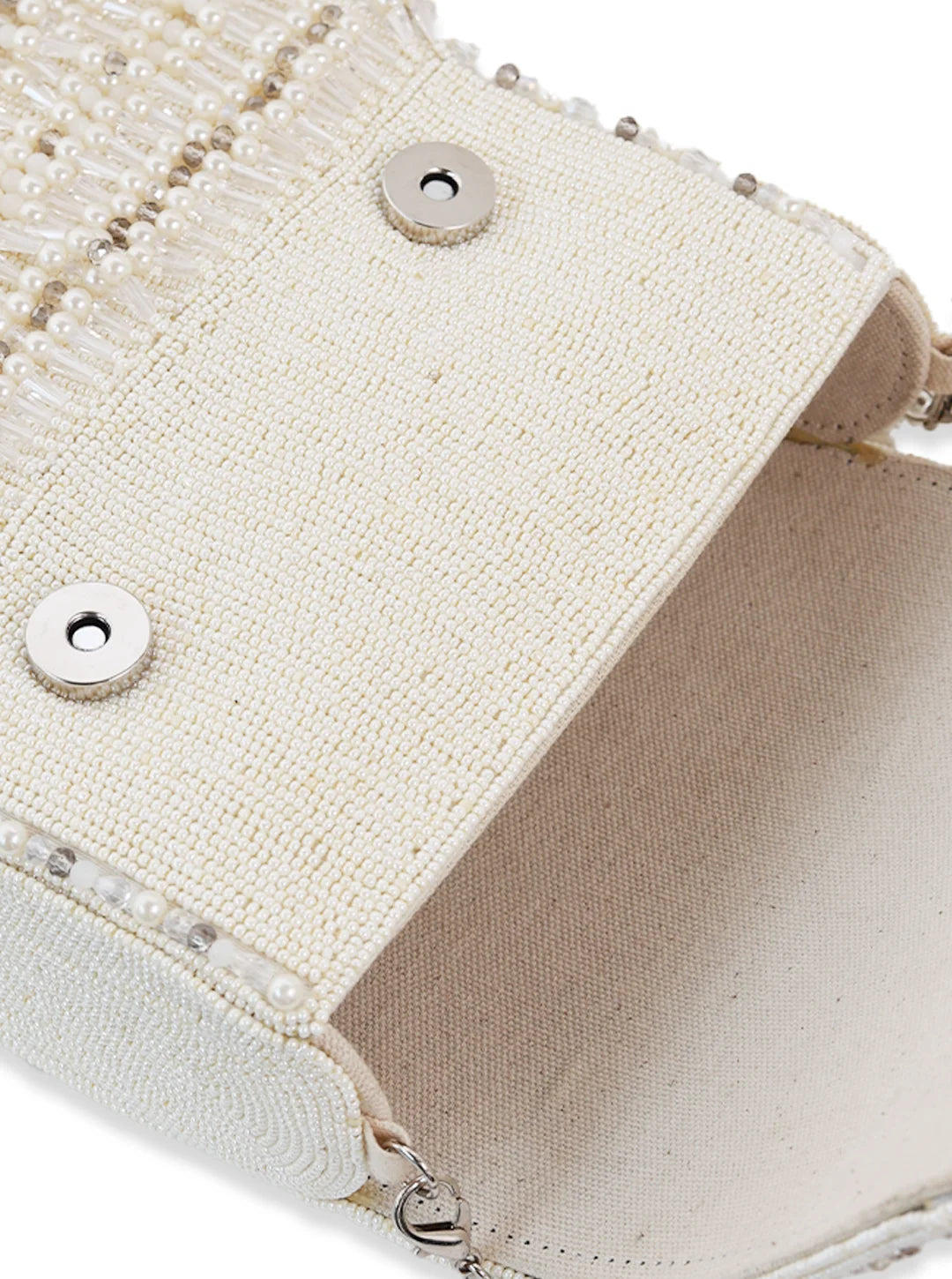 Close-up of a beige handbag with decorative elements and a zipper.