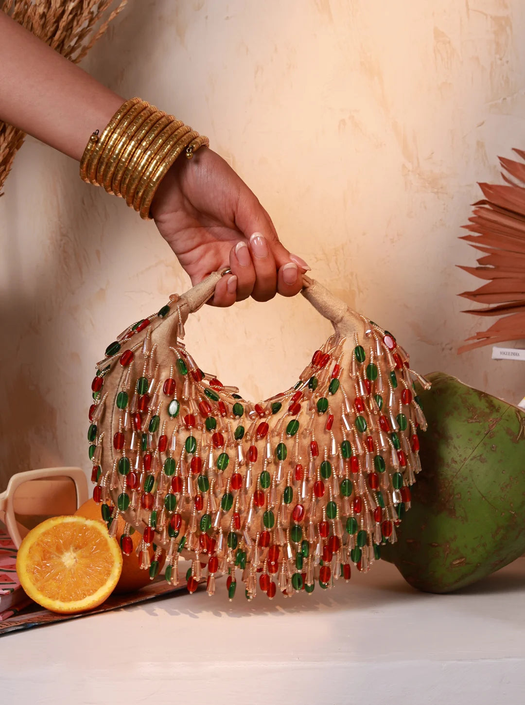 Hand holding a beaded handbag with fruits in the background