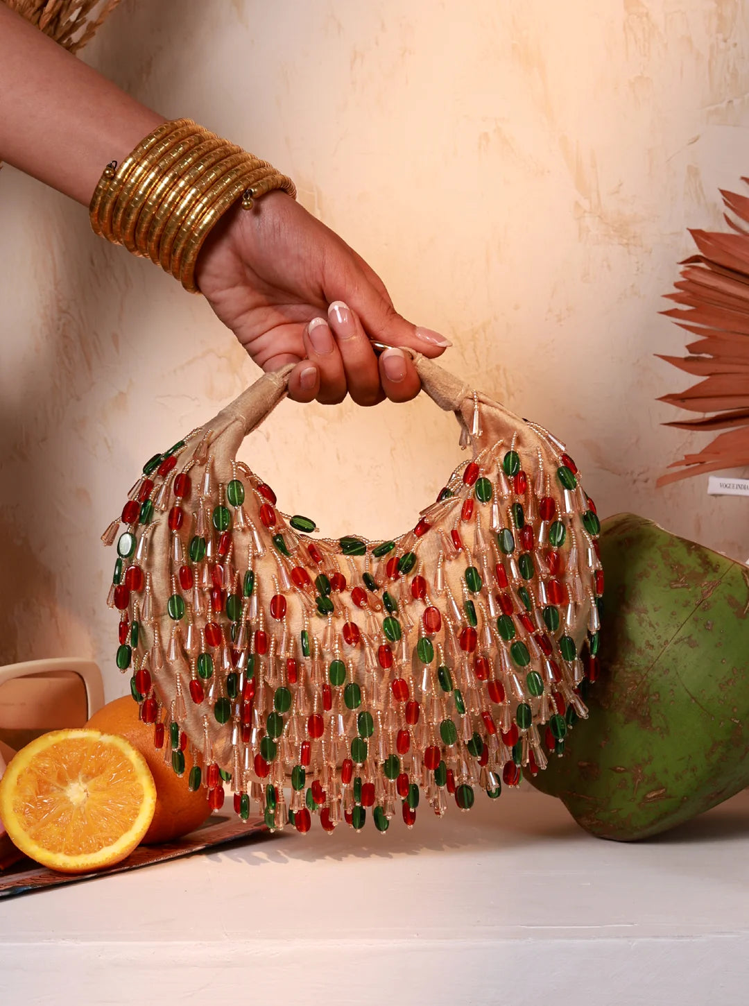 Hand holding a beaded handbag with fruits in the background