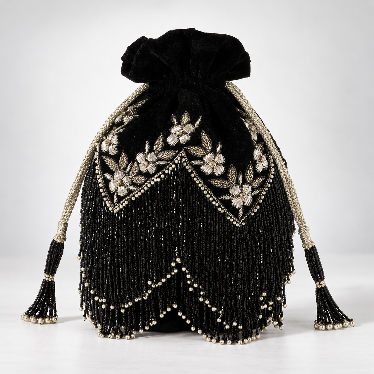 Black tassel potli bag with handle from The Tan Clan, featuring intricate embroidery and traditional design.
