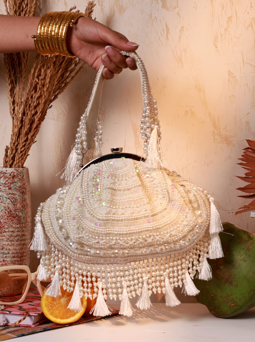 White Nora tasselled half moon Batua bag by The Tan Clan with tassel accents and a sleek, stylish design.