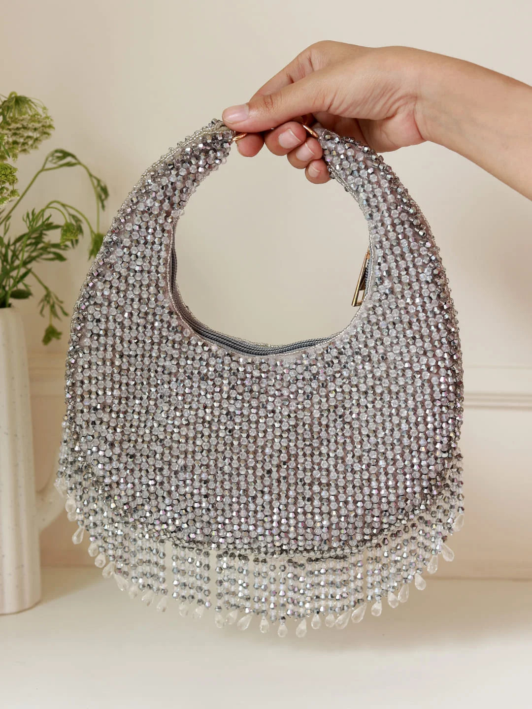 Hand holding a beaded handbag with a neutral background