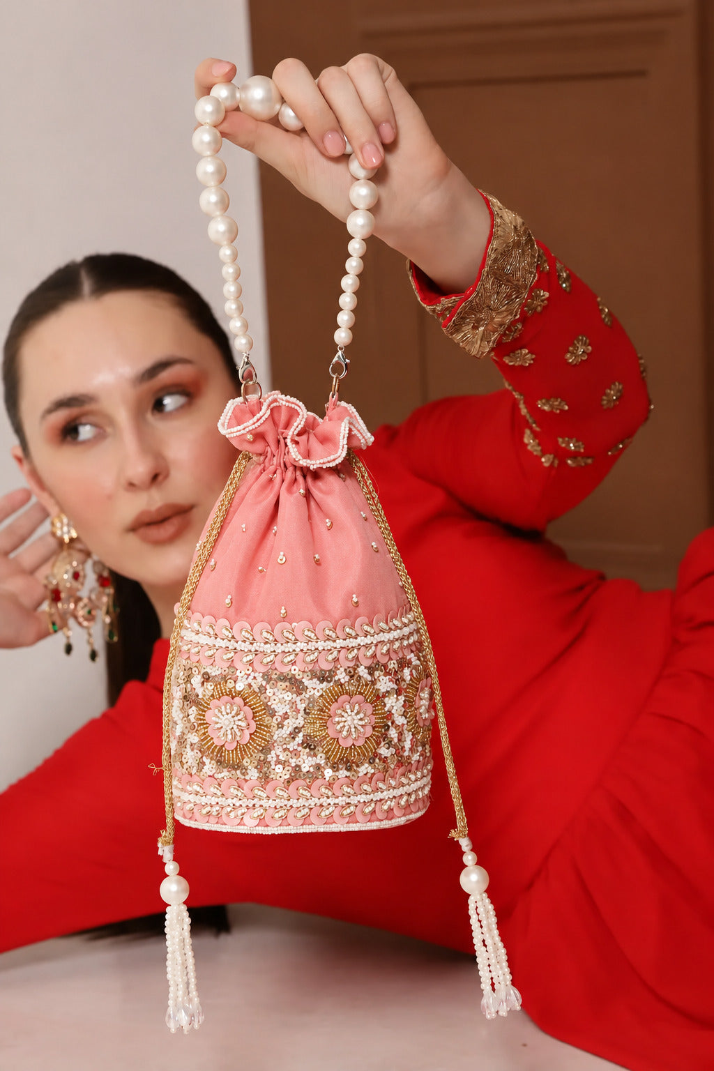 Pink Ama Potli bag with pearl handle from The Tan Clan, featuring traditional embroidery and elegant design.