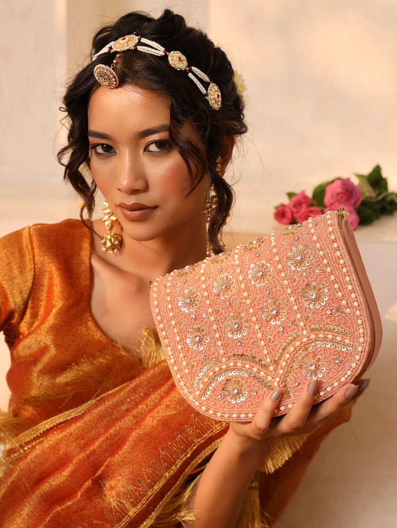 Pink flap-over bag with handle from The Tan Clan, featuring a stylish design and spacious interior.