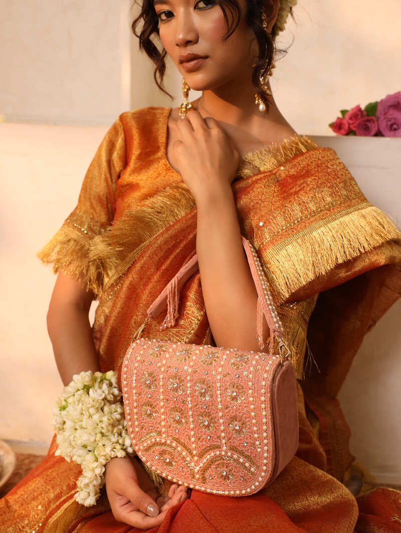 Pink flap-over bag with handle by The Tan Clan, featuring a stylish design and spacious interior for everyday use.