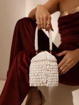 White round embellished bag with handle by The Tan Clan, featuring decorative accents and a stylish design.