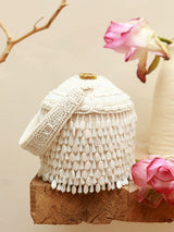 White round embellished bag with handle from The Tan Clan, featuring decorative details and a sleek design.