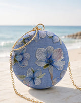 Blue embroidered clutch bag by The Tan Clan, featuring intricate floral embroidery and a sleek, compact design.