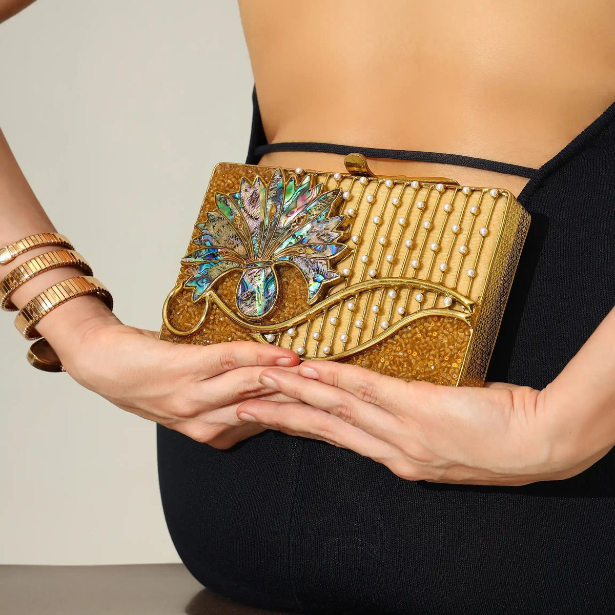 Elena brass clutch by The Tan Clan featuring a sleek, metallic design with a fold-over flap and minimalist style.