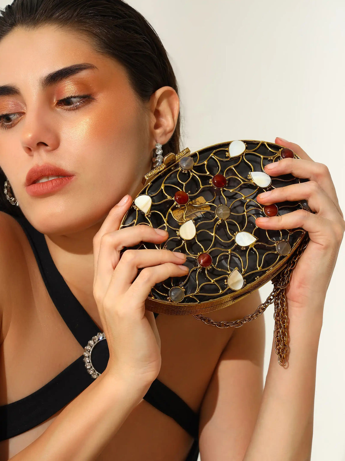 The Tan Clan Rhea Brass Clutch featuring a sleek, shiny brass finish and minimalist design for elegant evening use.