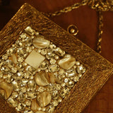 A brass clutch with intricate embellishments by The Tan Clan, showcasing detailed craftsmanship and elegant design.