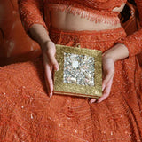 A brass clutch with intricate embellishments featuring a sleek design and metallic finish, crafted by The Tan Clan.