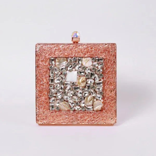A brass clutch by The Tan Clan with intricate embellishments, featuring a sleek design and elegant craftsmanship.