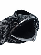 Black Batua bag with detachable handle by The Tan Clan, featuring sleek design and versatile styling options.