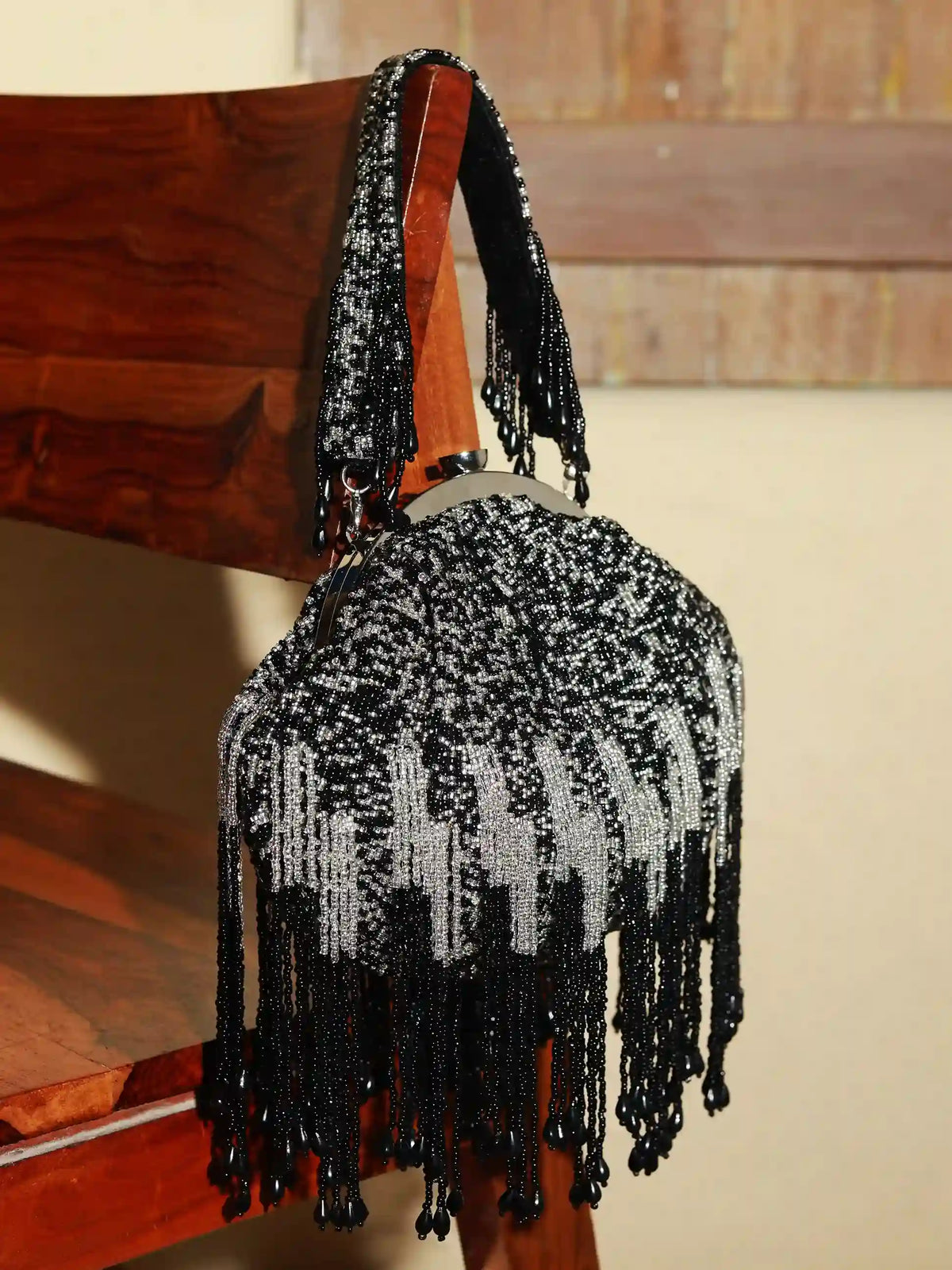 Black Batua bag by The Tan Clan with a detachable handle, featuring a sleek design and textured leather finish.
