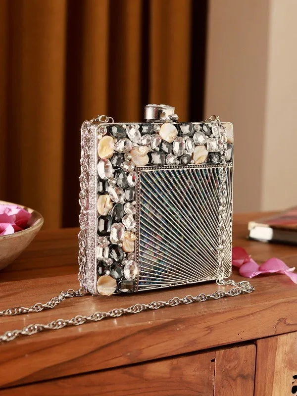 A brass clutch bag with intricate embellishments, featuring a sleek design and a decorative clasp from The Tan Clan's Aqsa collection.