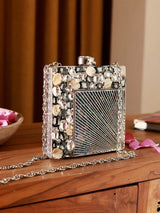 A brass clutch bag with intricate embellishments, featuring a sleek design and a decorative clasp from The Tan Clan's Aqsa collection.