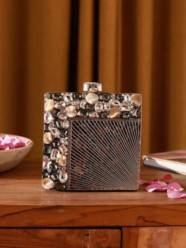 A brass embellished clutch bag with intricate detailing, designed by The Tan Clan, showcasing a stylish compact accessory.