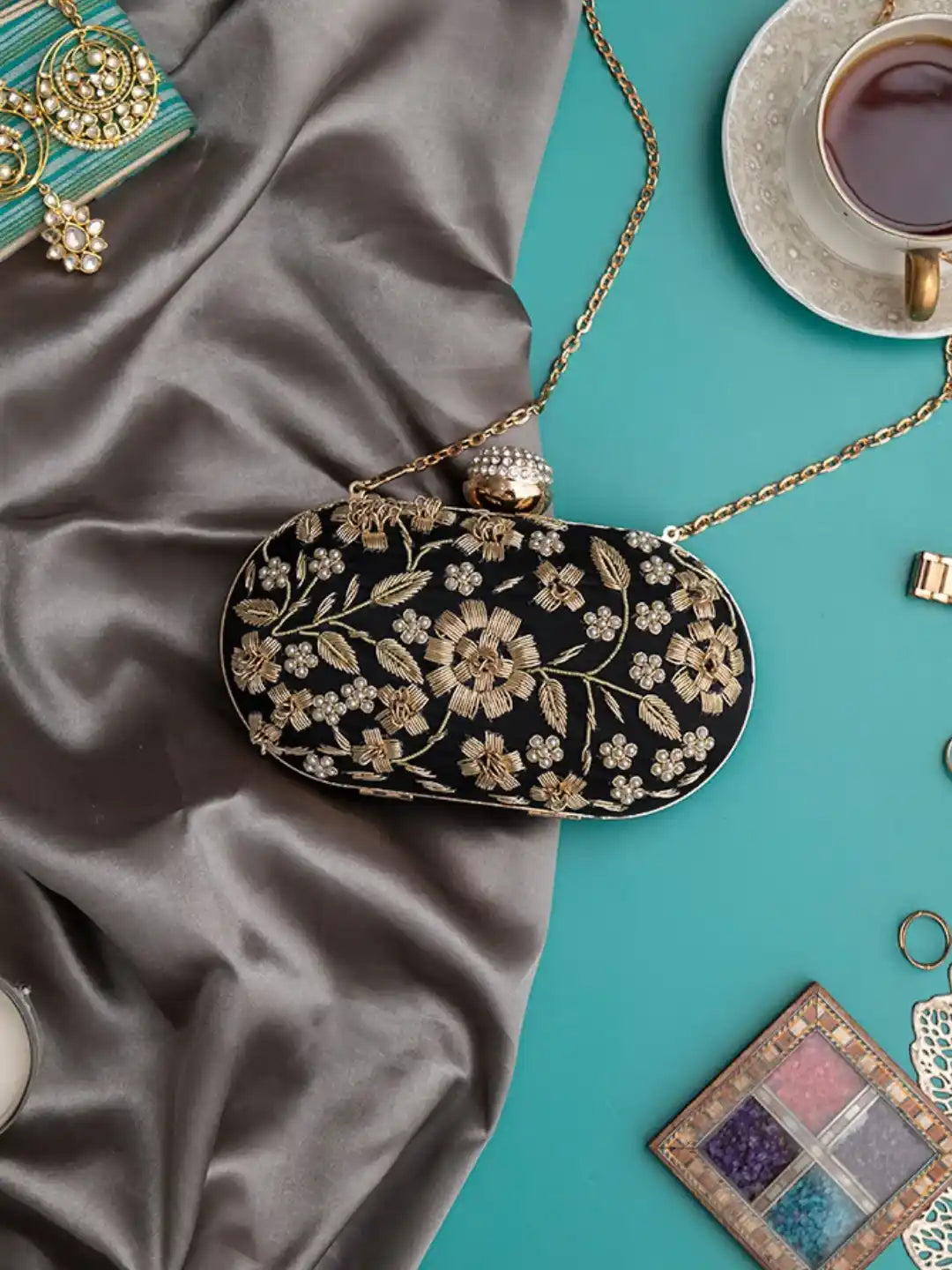 Elegant Baiza Zardozi hand-embroidered clutch by The Tan Clan with intricate gold and silver embroidery on a dark fabric background.