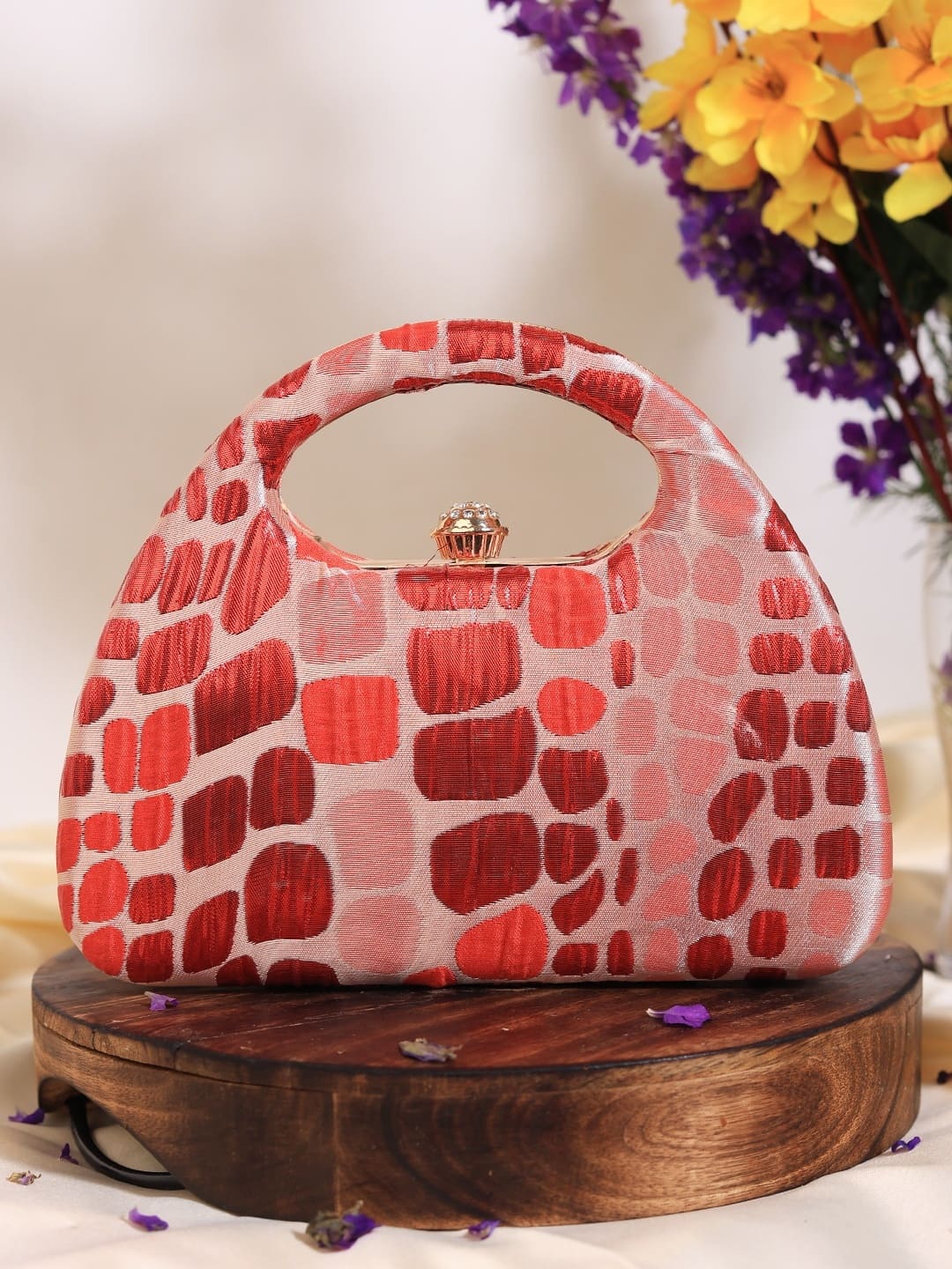 Red coral arc clutch by The Tan Clan with sleek design and gold-tone accents, perfect for evening or special occasions.