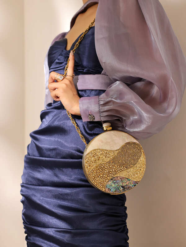 Crescent-shaped Mother of Pearl clutch bag by The Tan Clan with iridescent, shimmering surface and gold-tone clasp detail.