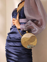 Crescent-shaped Mother of Pearl clutch bag by The Tan Clan with iridescent, shimmering surface and gold-tone clasp detail.