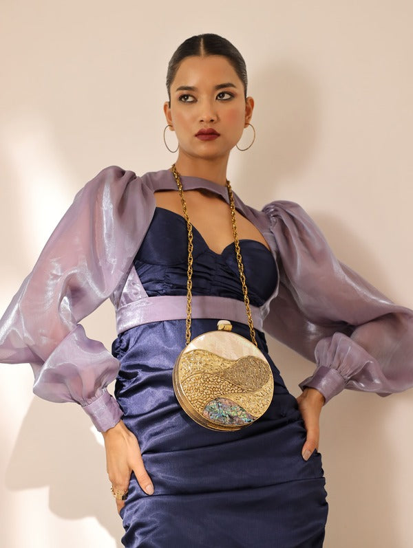 Crescent-shaped round clutch bag with mother of pearl finish and metallic clasp, designed by The Tan Clan.