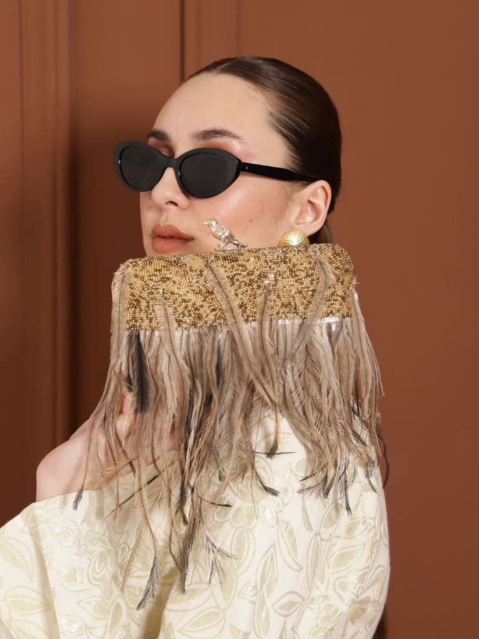 Dark gold feather embroidered clutch bag with hand-stitched details by The Tan Clan, featuring intricate embroidery and a sleek design.